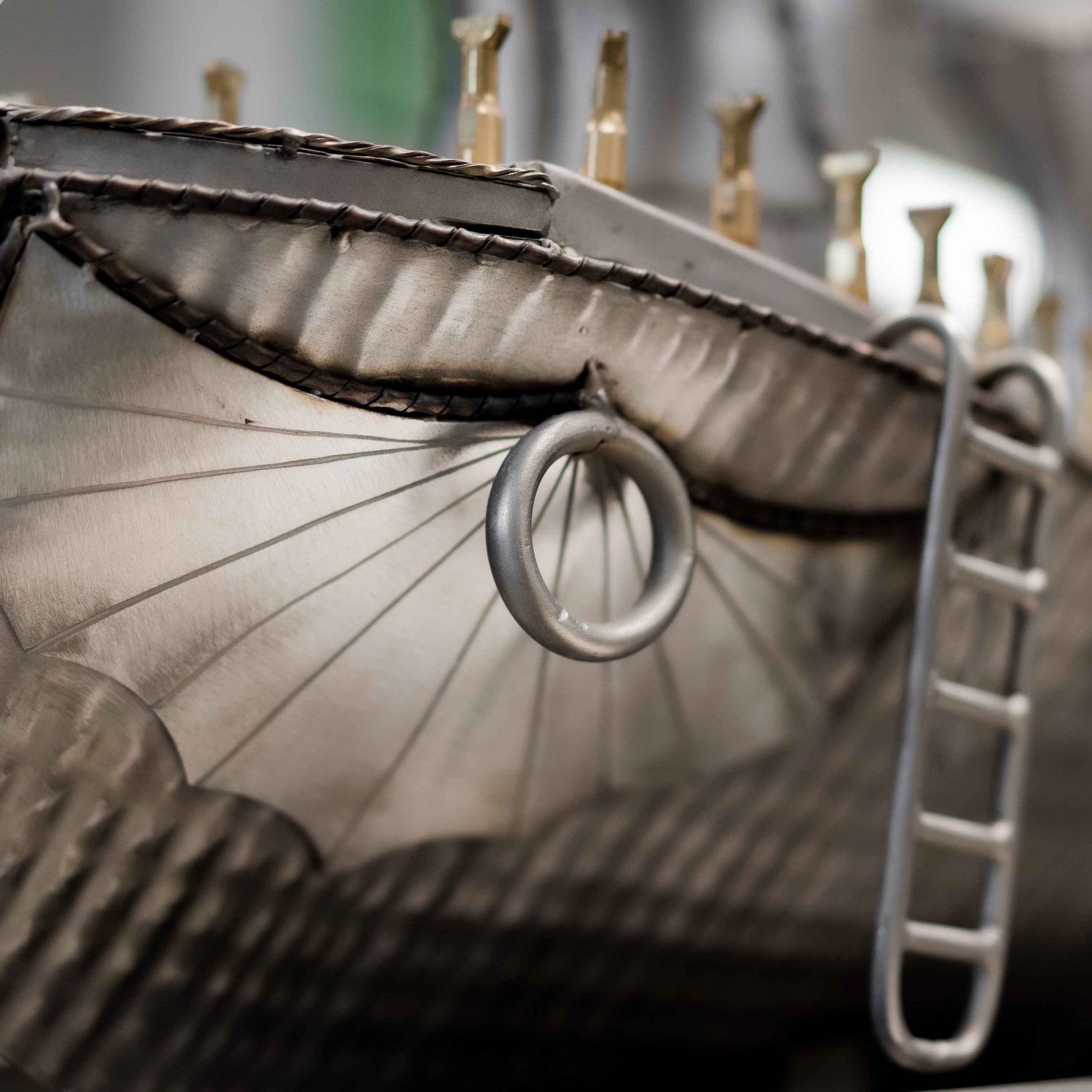 Close-up of a metal model ship with detailed rigging and sails.