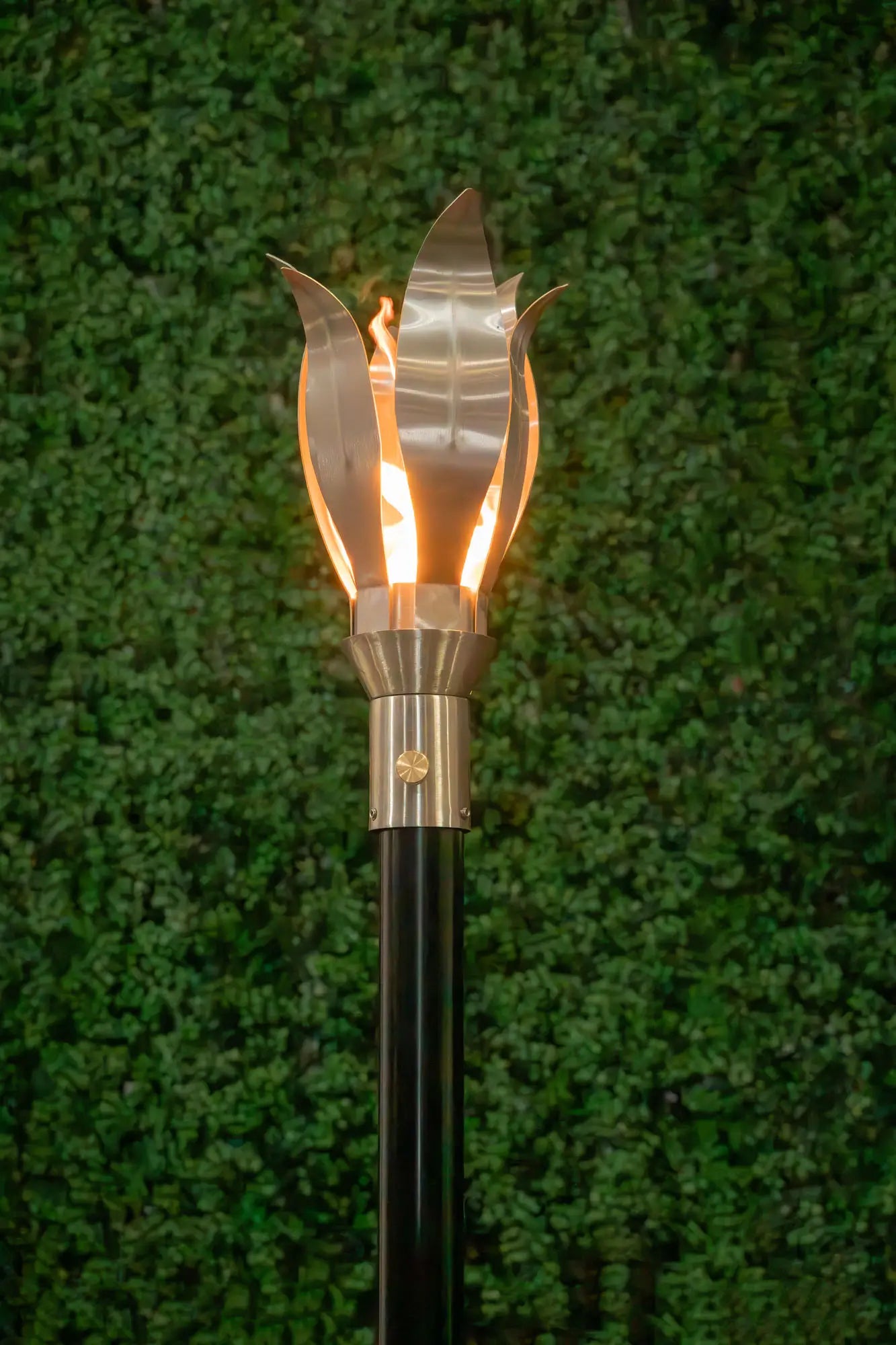 Decorative outdoor torch with flame-like design against a green background. What’s Included

Stainless steel flower-style torch head
In-ground post for landscape installation
Deck-mount adapter plate for hardscape mounting
8′ propane regulator and flex hose (for LP model)
Key valve for manual ignition
Installation and care instructions
Product Warranty

Lifetime Warranty on the burner system (residential use)
1-Year Warranty on valve and ignition components (6 months commercial)
Warranty valid when installe